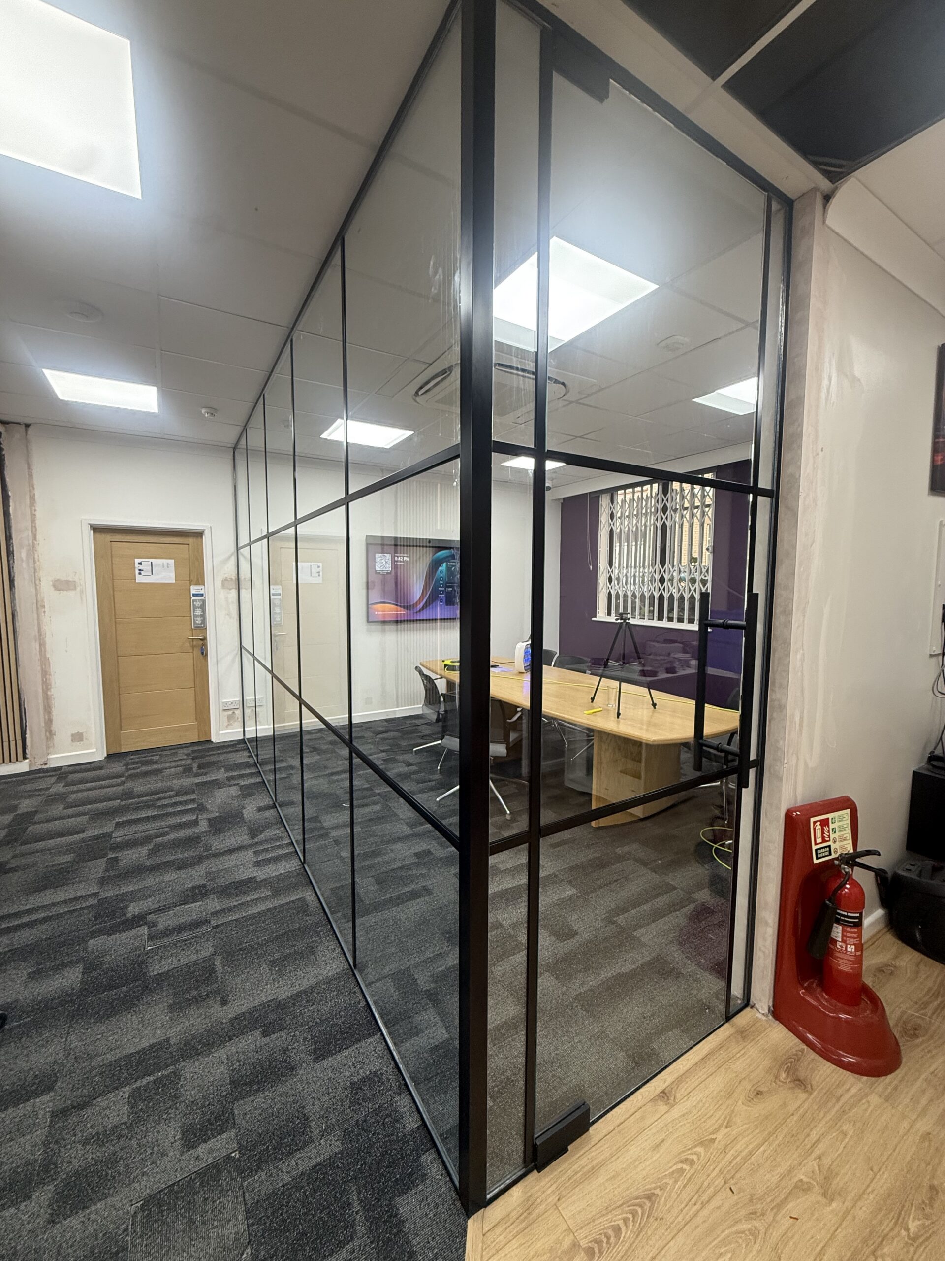 Full-height Crittall-style glazed office wall with black grid bars in West London